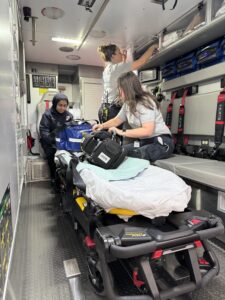 two EMTs check equipment in the back of the ambulance